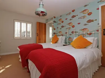 a bedroom with two beds with red and white sheets at Trelan in St Austell