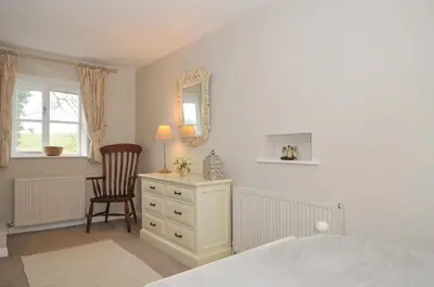 a bedroom with a bed and a chair and a mirror at Stocks Barn in Liskeard