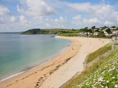 a beach with footprints in the sand and the ocean at Halvosso in Penryn