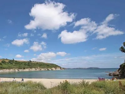 a beach with people walking on the sand and the water at Halvosso in Penryn