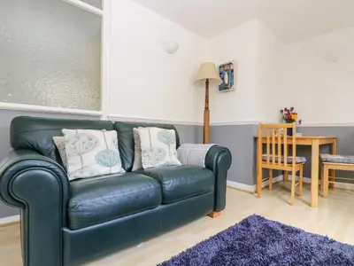 a green leather couch in a living room with a table at Little Beach House in St Austell