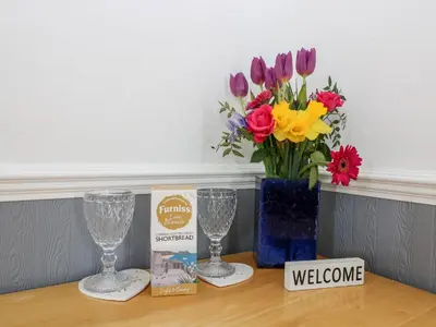 a table with two wine glasses and a vase of flowers at Little Beach House in St Austell