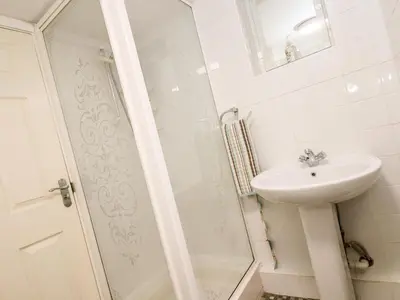 a white bathroom with a sink and a shower at Little Beach House in St Austell