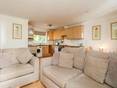 a living room with two couches and a kitchen at Tre Pol Pen in Falmouth