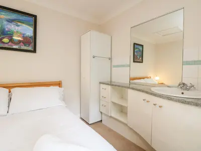 a white bathroom with a bed and a sink at Tre Pol Pen in Falmouth