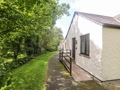 a white cottage with a fence next to a road at Tre Pol Pen in Falmouth