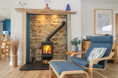 a living room with a fireplace and a blue chair at Higher Mount View in Marazion