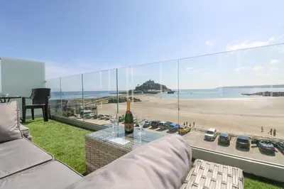 a living room with a couch and a view of a beach at Higher Mount View in Marazion