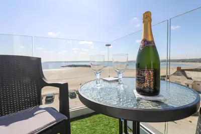 a bottle of champagne sitting on a table with two glasses at Higher Mount View in Marazion