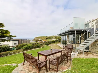 a wooden table and benches in front of a house at Little Trelawns in Mawgan Porth