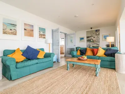 a living room with two blue couches and a coffee table at Little Trelawns in Mawgan Porth