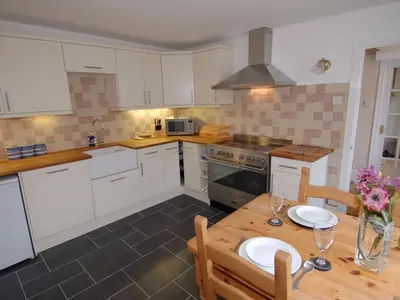 a kitchen with white cabinets and a wooden table at Jordan House in Boscastle