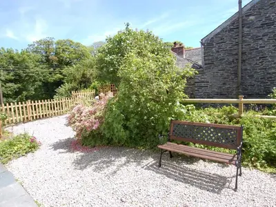a wooden bench sitting in front of a garden at Jordan House in Boscastle