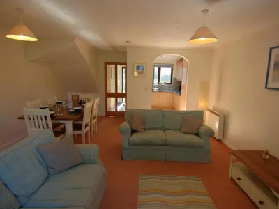 a living room with two couches and a dining room at Pine Cottage in Falmouth