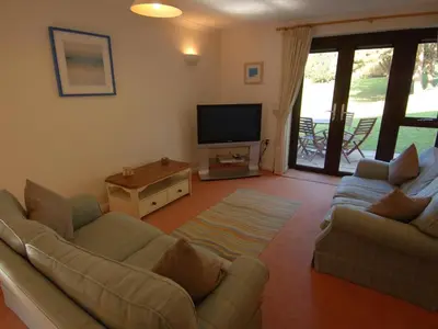 a living room with two couches and a flat screen tv at Pine Cottage in Falmouth
