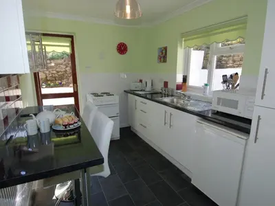 a kitchen with white cabinets and a black counter top at Trevillas in St Austell
