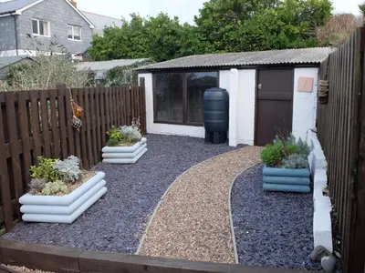a garden with three potted plants in front of a fence at The Keep Pot in Port Isaac