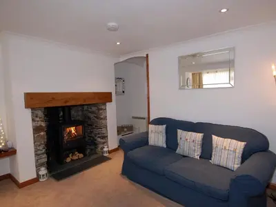 a living room with a blue couch and a fireplace at The Keep Pot in Port Isaac