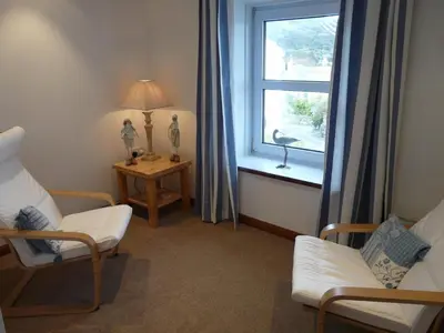 a living room with a window and two chairs and a table at The Keep Pot in Port Isaac