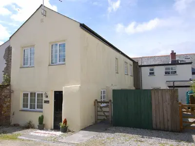 a large white house with a green fence at The Barn in Camelford