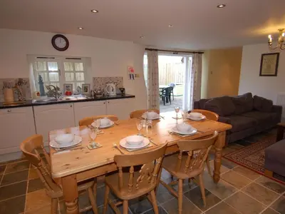 a wooden table and chairs in a living room at The Barn in Camelford