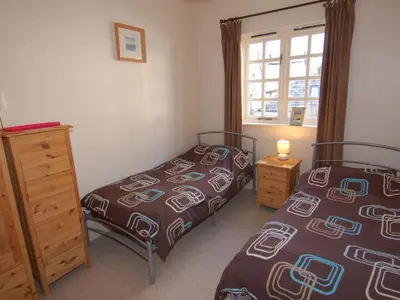 a bedroom with two beds and a dresser and a window at The Barn in Camelford