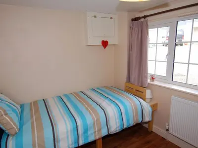 a small bedroom with a bed and a window at The Barn in Camelford