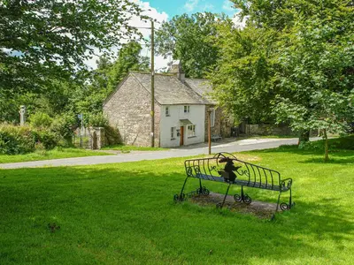 a park bench with a statue of a person sitting on it at Churchgate Cottage in Bodmin