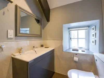a bathroom with a sink and a mirror and a toilet at Churchgate Cottage in Bodmin