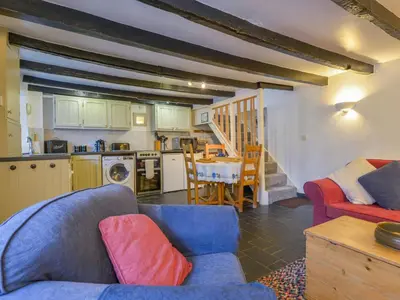 a living room with a blue couch and a kitchen at Churchgate Cottage in Bodmin
