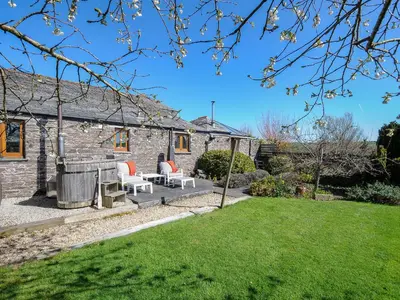a stone cottage with a patio and lawn at Swallow Barn in Saint Kew