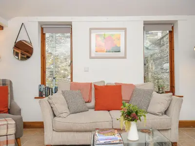 a living room with a couch and some windows at Swallow Barn in Saint Kew