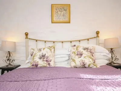 a bedroom with a bed with purple sheets and pillows at Swallow Barn in Saint Kew