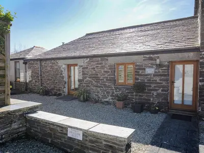 a stone house with a stone bench in front of it at Swallow Barn in Saint Kew