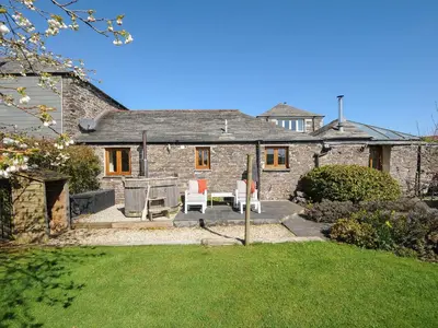 a stone house with a patio and a yard at Swallow Barn in Saint Kew