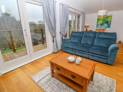 a living room with a blue couch and a coffee table at 1 Lake View in Looe