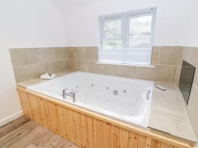 a large white tub in a bathroom with a window at 1 Lake View in Looe