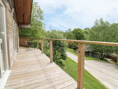 a wooden deck with a table on a house at 1 Lake View in Looe