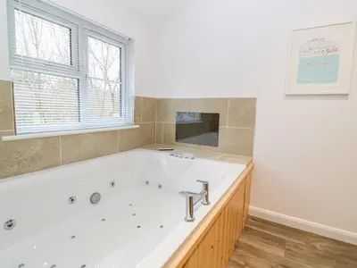 a large bathroom with a tub and a window at 1 Lake View in Looe