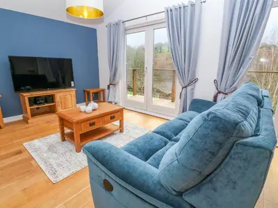 a living room with a blue couch and a tv at 1 Lake View in Looe