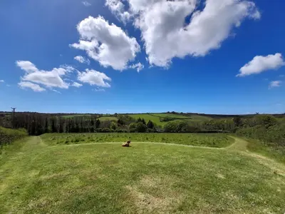 a large grassy field with a blue sky and clouds at Higher Lampra in Helston