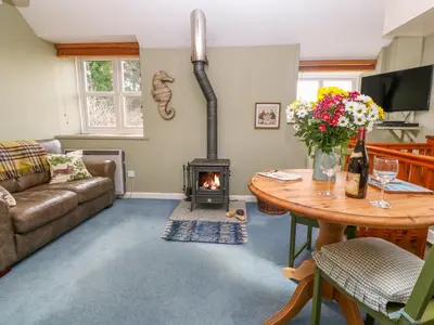 a living room with a fireplace and a table at Higher Lampra in Helston