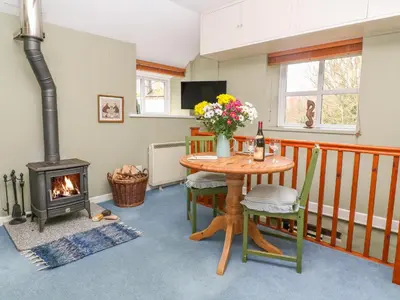 a living room with a table and a fireplace at Higher Lampra in Helston