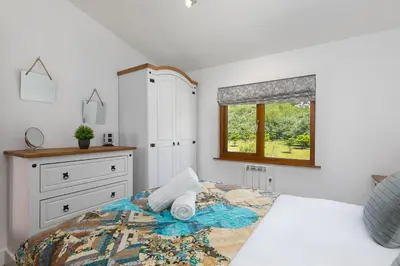 a bedroom with a bed with a dresser and a window at Costentyn, Tor Down Quarry in Bodmin