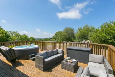 a deck with a hot tub and a couch and chairs at Costentyn, Tor Down Quarry in Bodmin