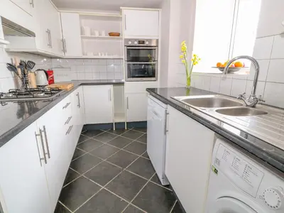 a white kitchen with a sink and a dishwasher at Blue Anchor in Saint Enoder