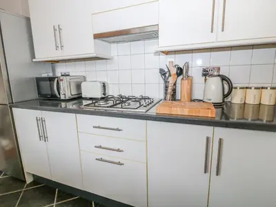 a kitchen with white cabinets and a stove top oven at Blue Anchor in Saint Enoder