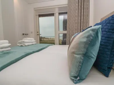 a bedroom with a large bed with blue pillows at Chapel Rock View, The Dunes in Perranporth