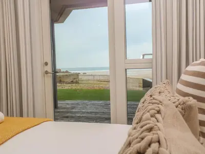 a bedroom with a bed and a view of the ocean at Chapel Rock View, The Dunes in Perranporth