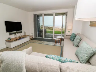 a living room with a couch and a television at Chapel Rock View, The Dunes in Perranporth